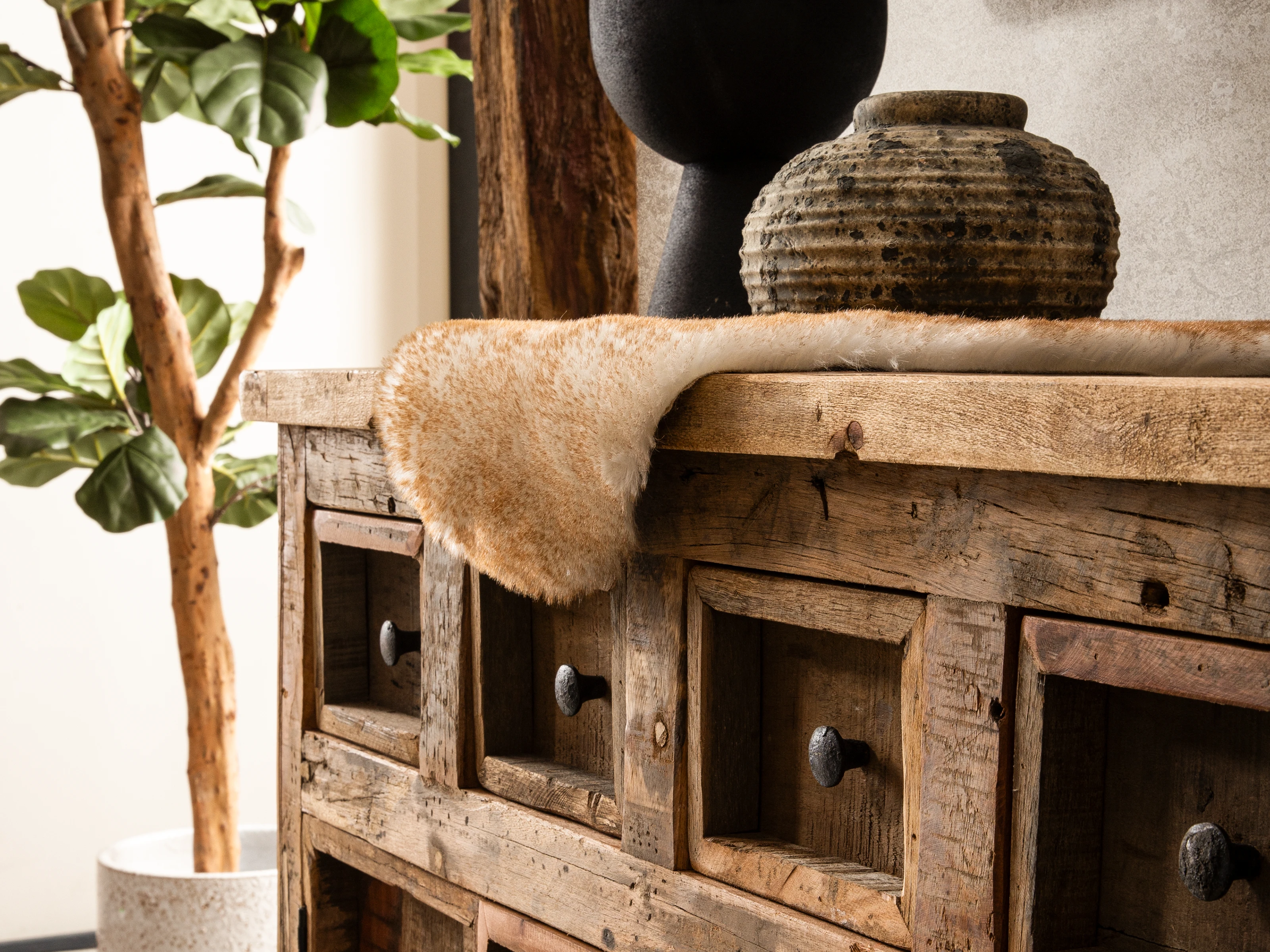 Detail eines massiven Holztisches in warmen Brauntönen mit sichtbarer Holzmaserung und geölter Oberfläche vor neutralem Ambiente