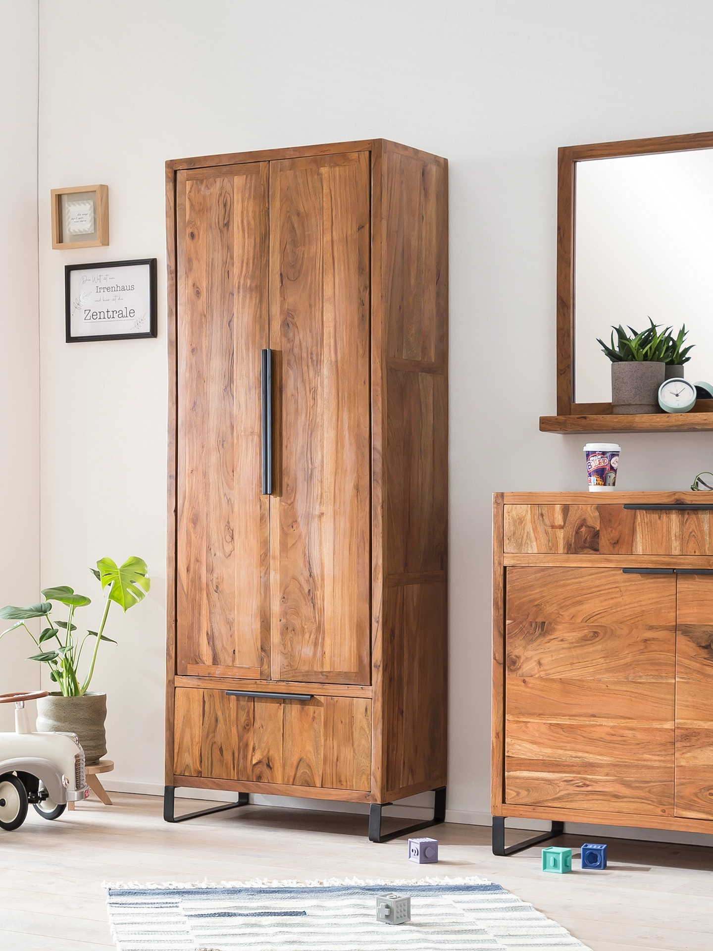 Hohes Holzregal "Sydney" in warmer Eichenoptik, modernes Ambiente mit Pflanzen und Deko, schlanke vertikale Form, natürliche Farbtöne und gemütliche Wohnraumstimmung